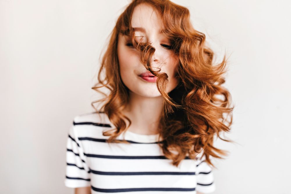 Woman with red curly permed hair in striped shirt